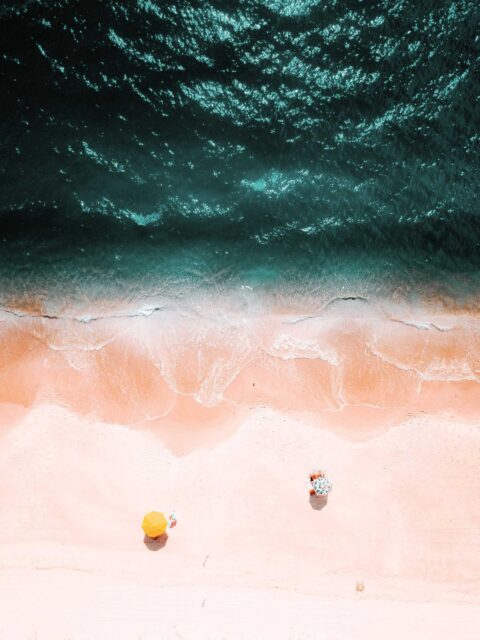 bird’s eye view of two yellow and green umbrellas on beach