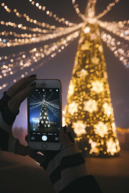 A person taking a picture of their Christmas tree with their smartphone.