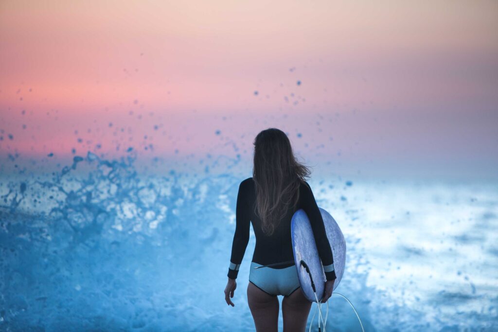 woman in black long sleeve shirt and white shorts standing on blue water during sunset