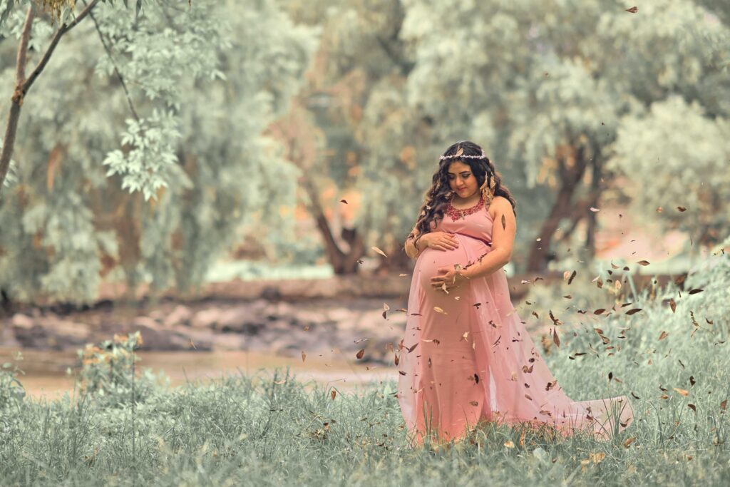 woman holding her pregnant tummy near tree