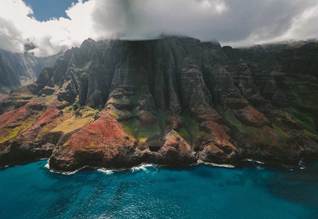 landscape photography of mountain beside body of water under cloudy sky