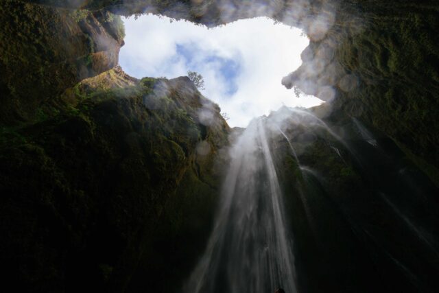 worm’s eye view photo of cave waterfalls