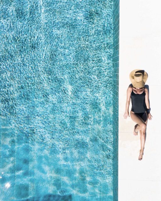 woman in black bikini bottom and white sun hat standing on blue water