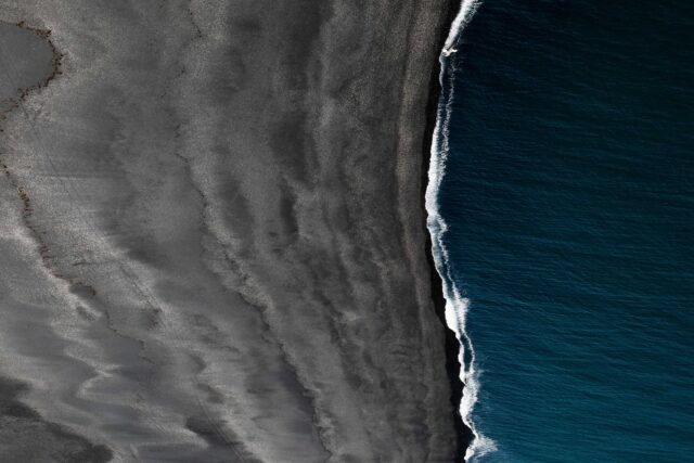 bird’s view of black sand and body of water