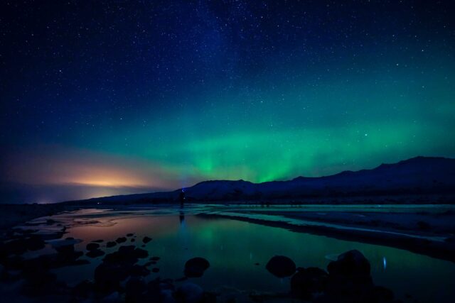 aurora borealis photography of body of water and mountain
