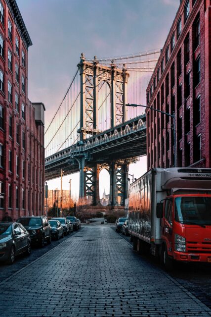 cars parked on both sides of street near bridge