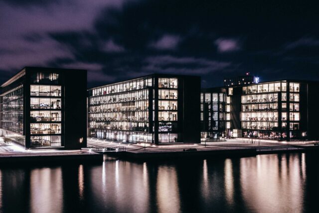 three concrete buildings near body of water during nighttime