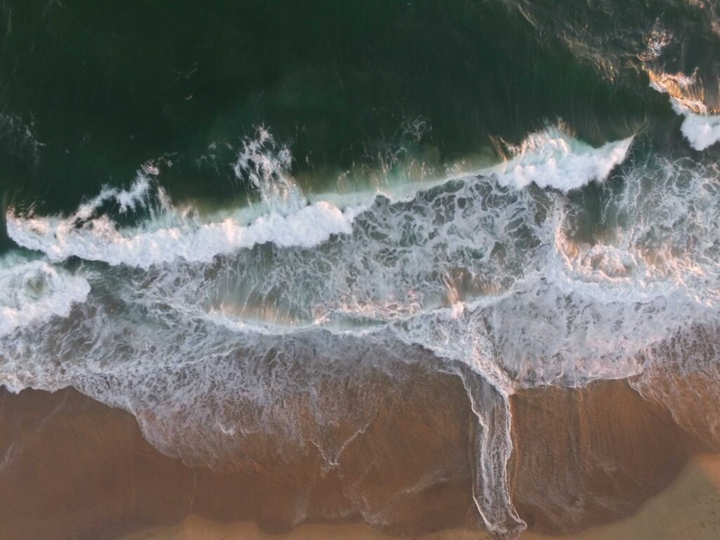 body of water splashing on a sand